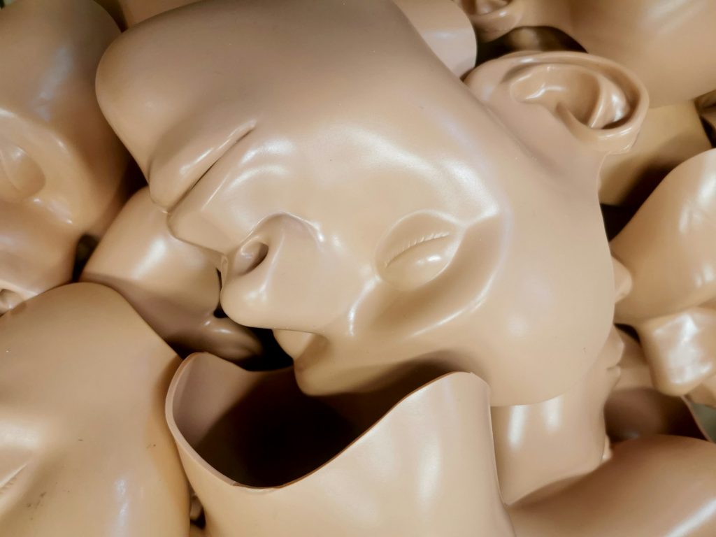 A pile of beige mannequin faces, evoking themes of identity, uniformity, and the struggle for individuality in a complex world.