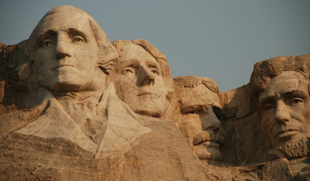 Close-up view of the four presidential faces carved into Mount Rushmore during golden hour.